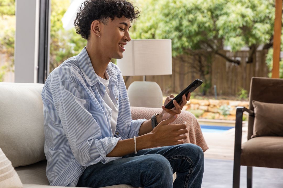 Man Relaxing with Smartphone on Sofa in Modern Living Space