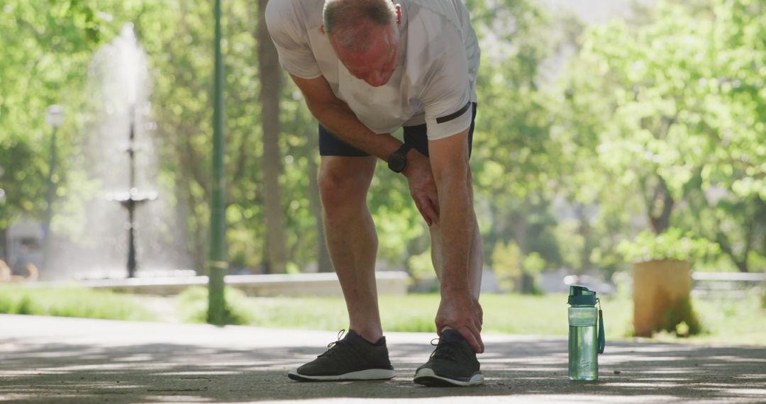 Senior Jogger Stretching in Park with Water Bottle Nearby - Free Images, Stock Photos and Pictures on Pikwizard.com