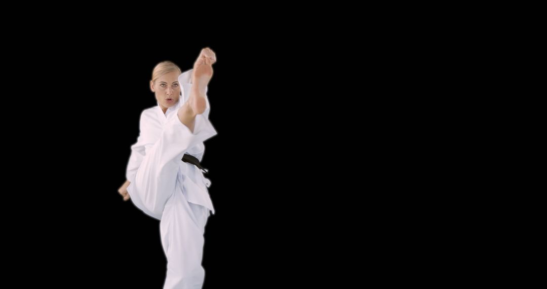 Woman Performing Karate Kick in White Gi on Black Background - Free Images, Stock Photos and Pictures on Pikwizard.com