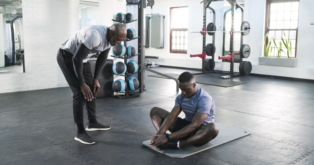 Trainer Helping Client with Butterfly Stretch in Modern Gym