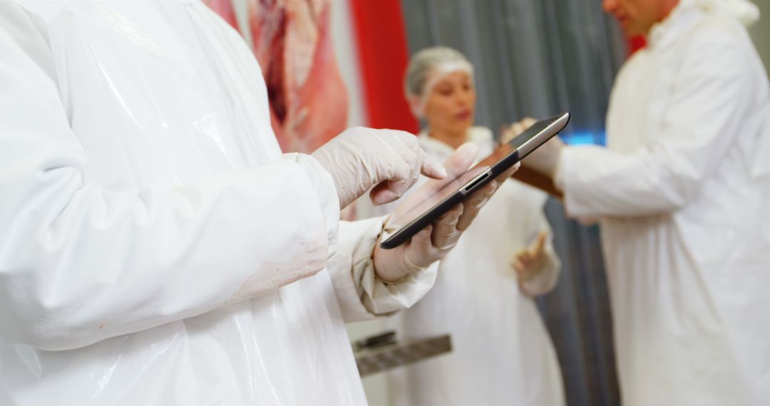 Meat Industry Workers Using Digital Tablet in Processing Facility - Free Images, Stock Photos and Pictures on Pikwizard.com