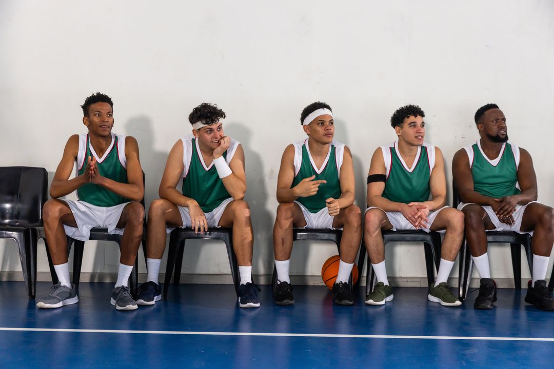 Diverse Basketball Team Resting on Sidelines in Gym