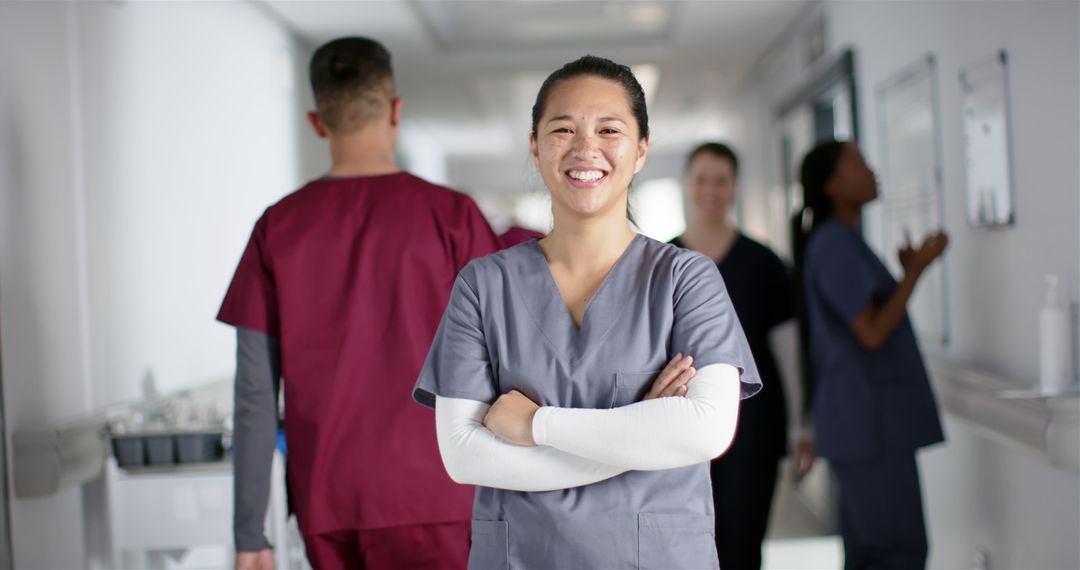 Confident Nurse Standing with Colleagues in Hospital Corridor - Free Images, Stock Photos and Pictures on Pikwizard.com