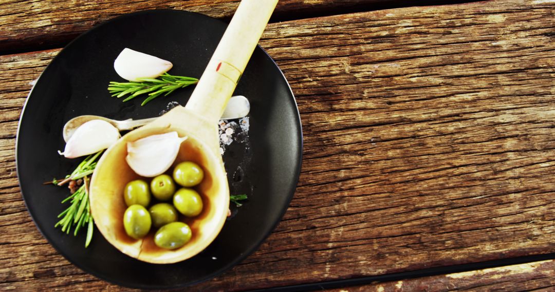 Rustic Wooden Table with Fresh Garlic, Olives and Herbs on Black Plate - Free Images, Stock Photos and Pictures on Pikwizard.com