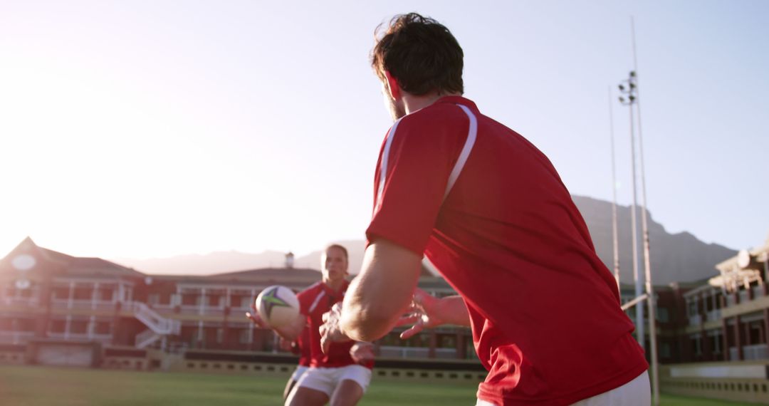 Rugby Players Passing Ball on Field During Sunset Practice - Free Images, Stock Photos and Pictures on Pikwizard.com