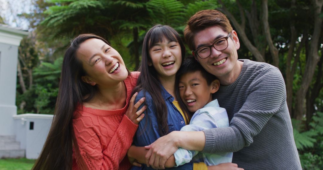 Portrait of smiling asian parents embracing laughing son and daughter in garden - Free Images, Stock Photos and Pictures on Pikwizard.com