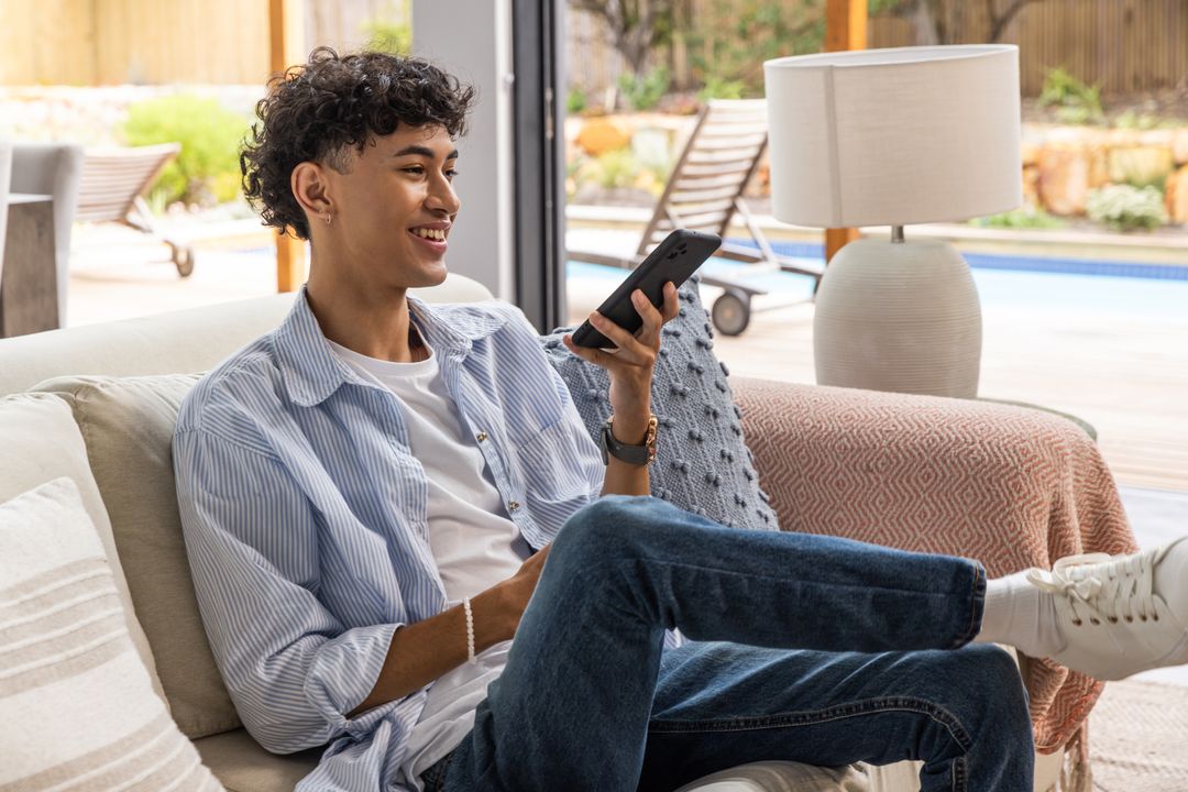Young Man Relaxing with Smartphone in Modern Home by Poolside