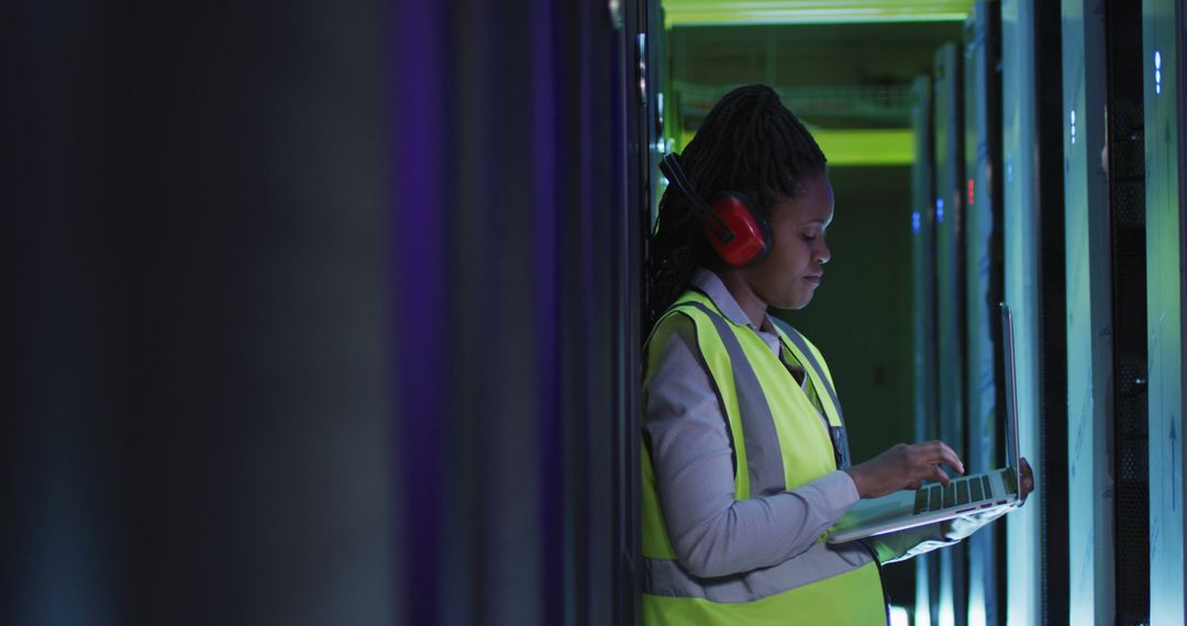 Woman in yellow vest working in data center with laptop and safety gear - Free Images, Stock Photos and Pictures on Pikwizard.com