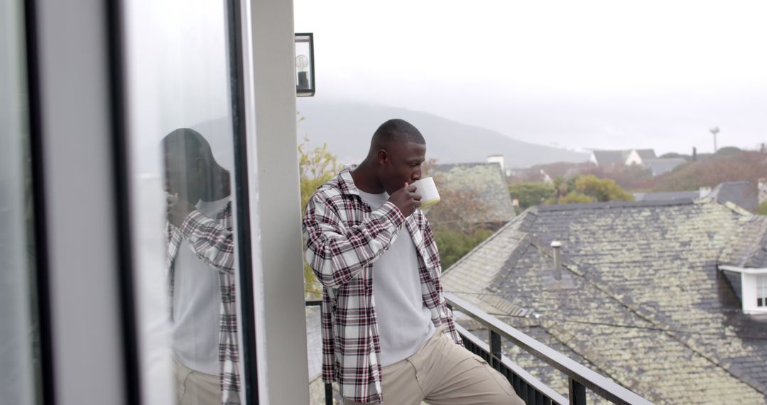 Man Enjoying Morning Coffee on Balcony Overlooking Scenic Town - Free Images, Stock Photos and Pictures on Pikwizard.com