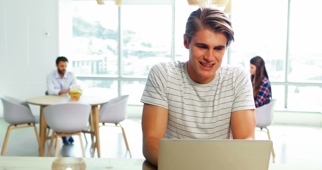 Young Man Working on Laptop in Modern Coworking Space - Free Images, Stock Photos and Pictures on Pikwizard.com