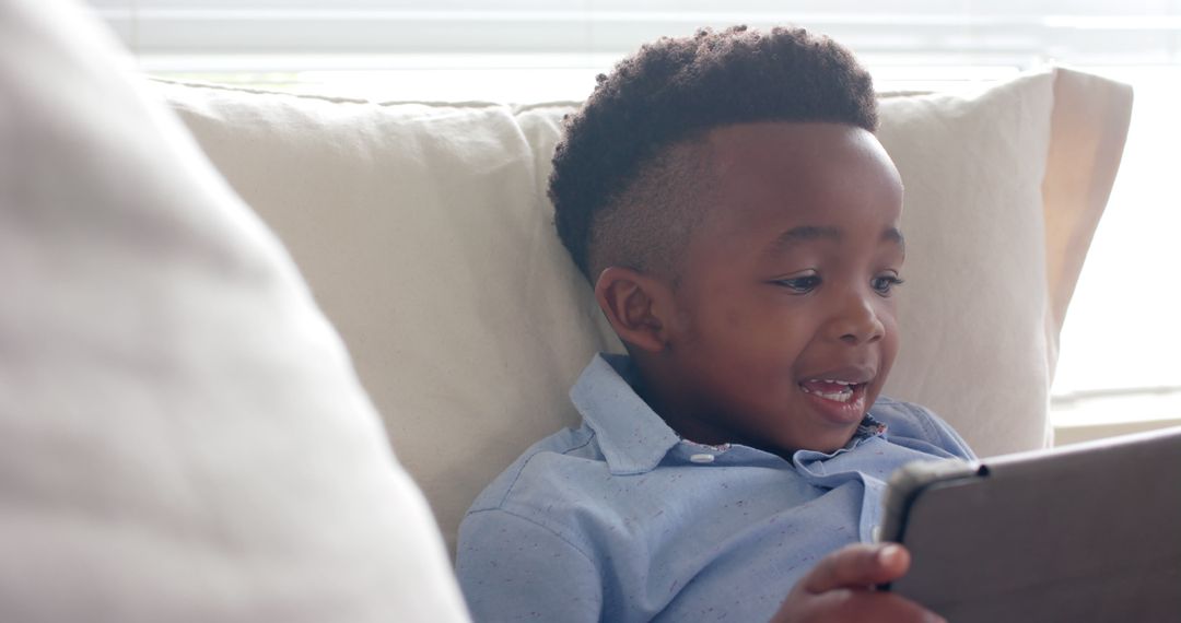 Young Boy Enthusiastically Using Tablet on Cozy Sofa