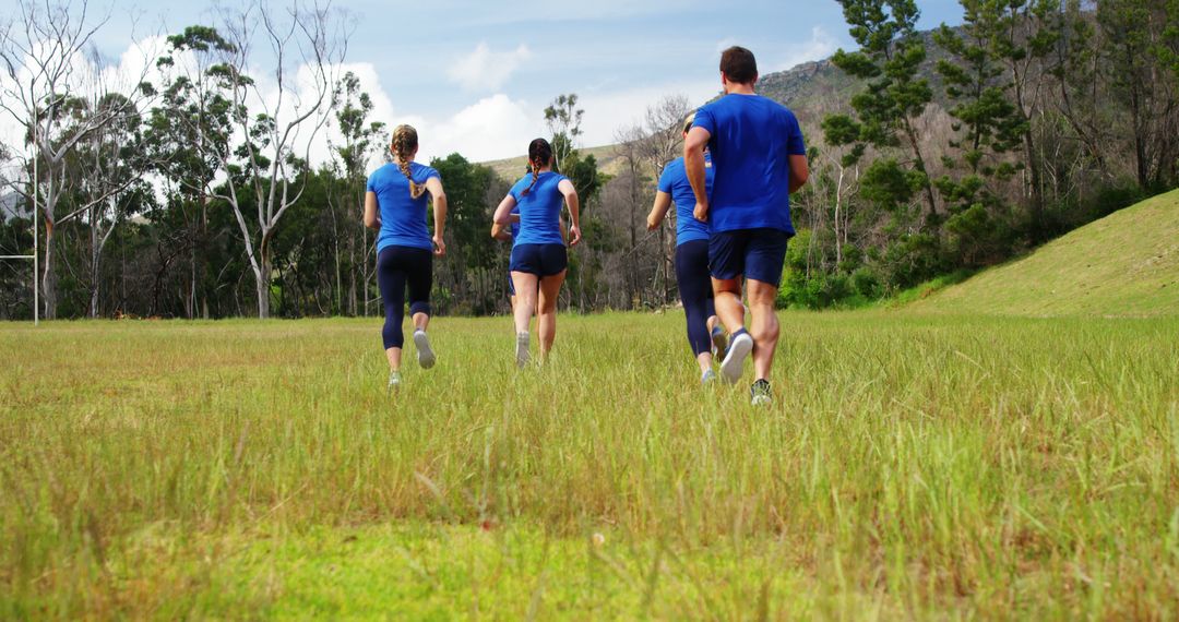 Group of Young Adults Jogging in Grassy Field for Fitness and Teamwork - Free Images, Stock Photos and Pictures on Pikwizard.com