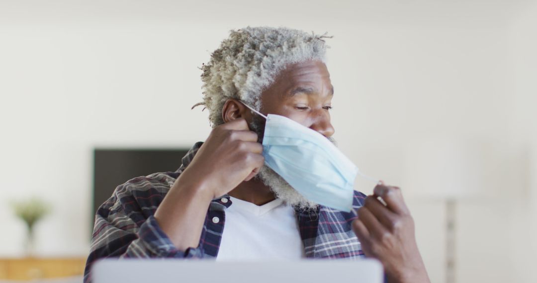 Senior African American Man Removing Face Mask at Home - Free Images, Stock Photos and Pictures on Pikwizard.com