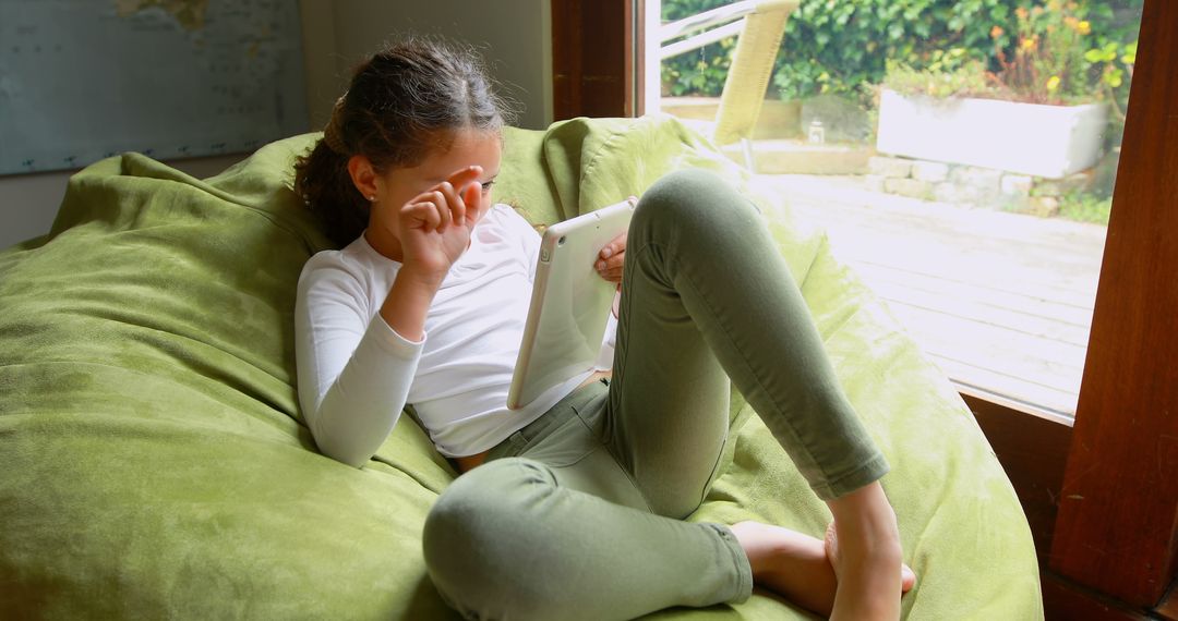 Child Relaxing on Beanbag with Tablet During Indoor Leisure - Free Images, Stock Photos and Pictures on Pikwizard.com