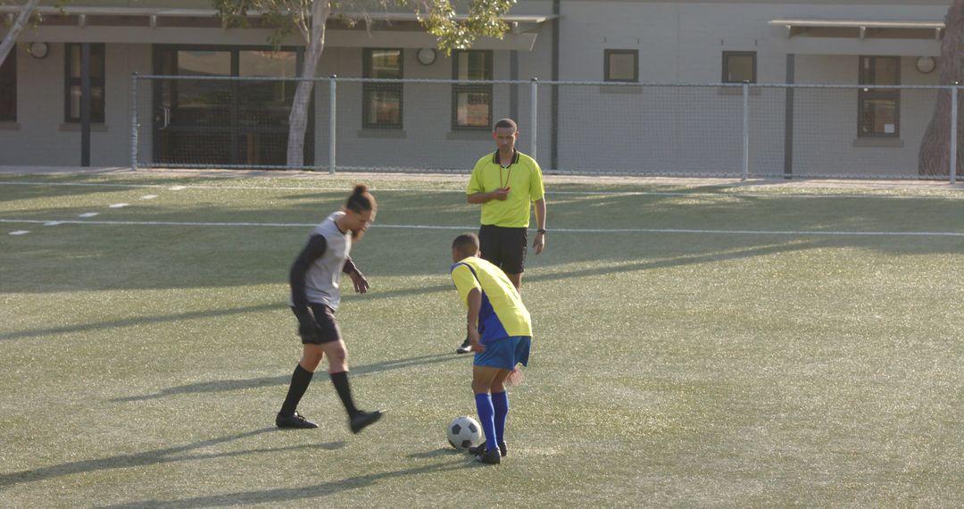 Referee Observing Players During Soccer Game Preparation on Sunny Field