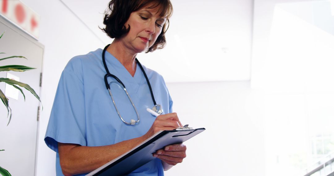 Medical Professional Writing on Clipboard in Light-Filled Room - Free Images, Stock Photos and Pictures on Pikwizard.com