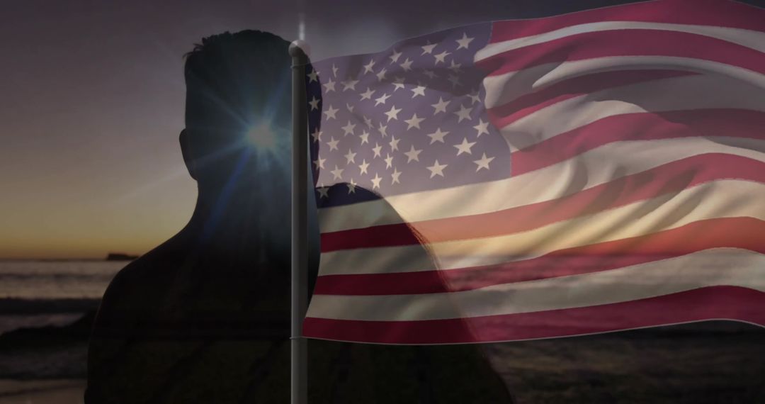 Silhouetted Man with Waving American Flag at Sunset on Ocean Shore