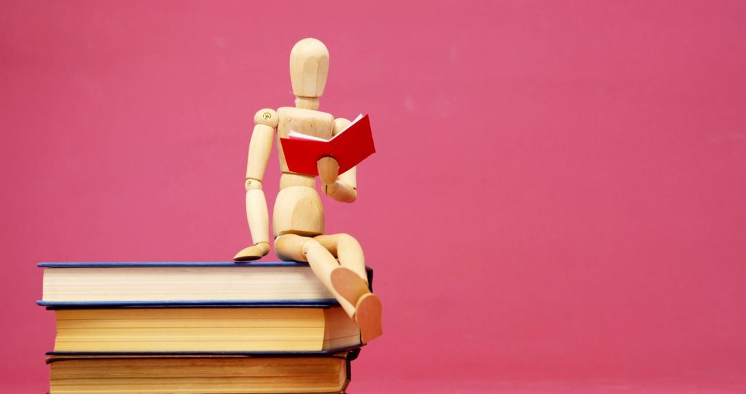 Wooden Figure Reading Book on Top of Stack of Books with Pink Background - Free Images, Stock Photos and Pictures on Pikwizard.com