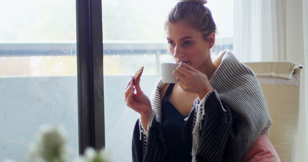 Young Woman Enjoying Coffee and Snack at Home by the Window - Free Images, Stock Photos and Pictures on Pikwizard.com