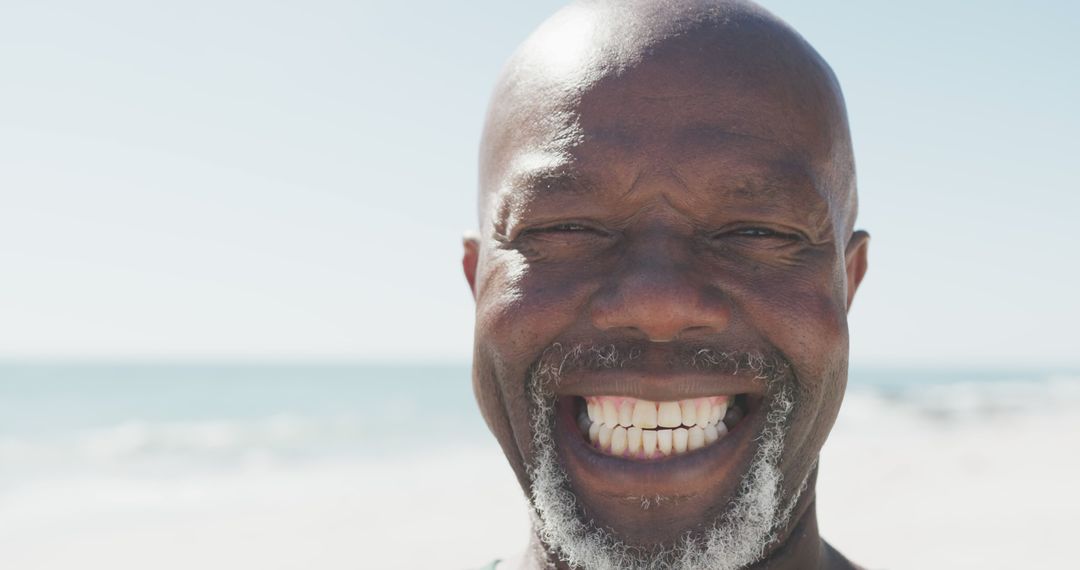 Smiling elderly man enjoying beach on a sunny day - Free Images, Stock Photos and Pictures on Pikwizard.com