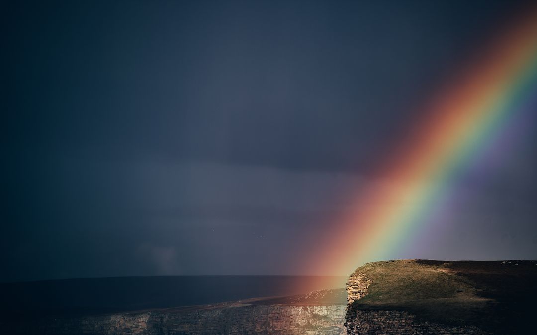 Bright Rainbow Over Cliffs With Dramatic Dark Sky - Free Images, Stock Photos and Pictures on Pikwizard.com