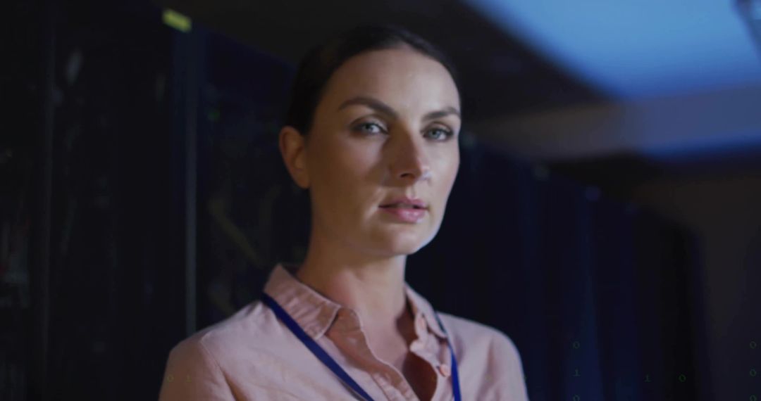 Female IT Technician Monitoring Server Racks in Blue-Lit Data Center Portrait with Lanyard