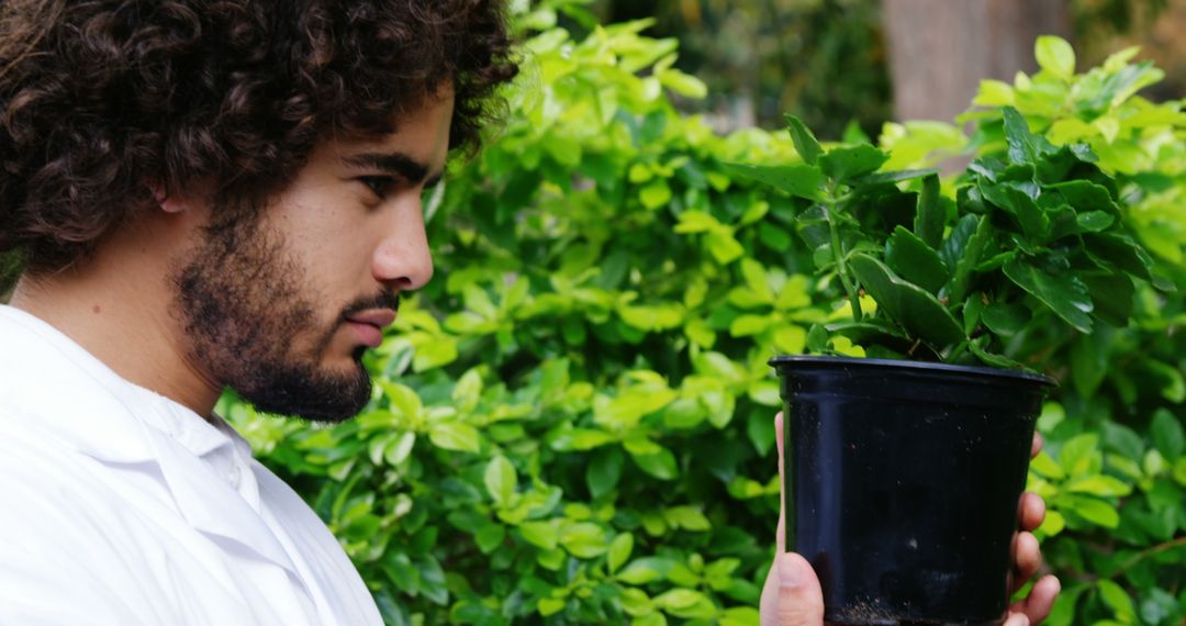 Horticulturist Carefully Examining Potted Plant in Garden - Free Images, Stock Photos and Pictures on Pikwizard.com