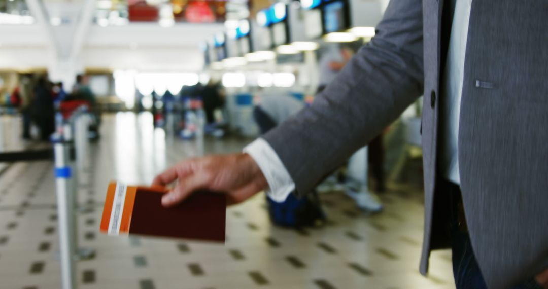 Businessman Holding Passport and Boarding Pass at Airport Terminal - Free Images, Stock Photos and Pictures on Pikwizard.com