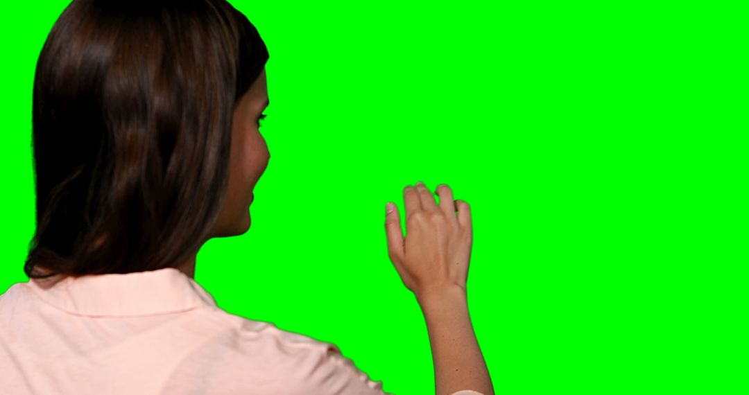 Woman pretending to touch digital screen against green screen - Free Images, Stock Photos and Pictures on Pikwizard.com