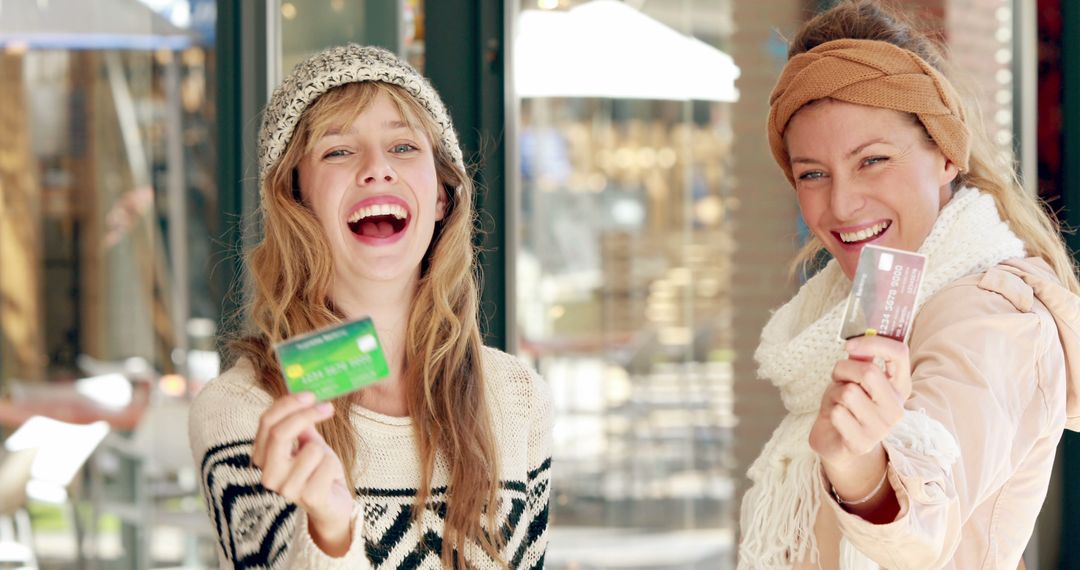 Two Women Laughing and Holding Credit Cards Outdoors - Free Images, Stock Photos and Pictures on Pikwizard.com