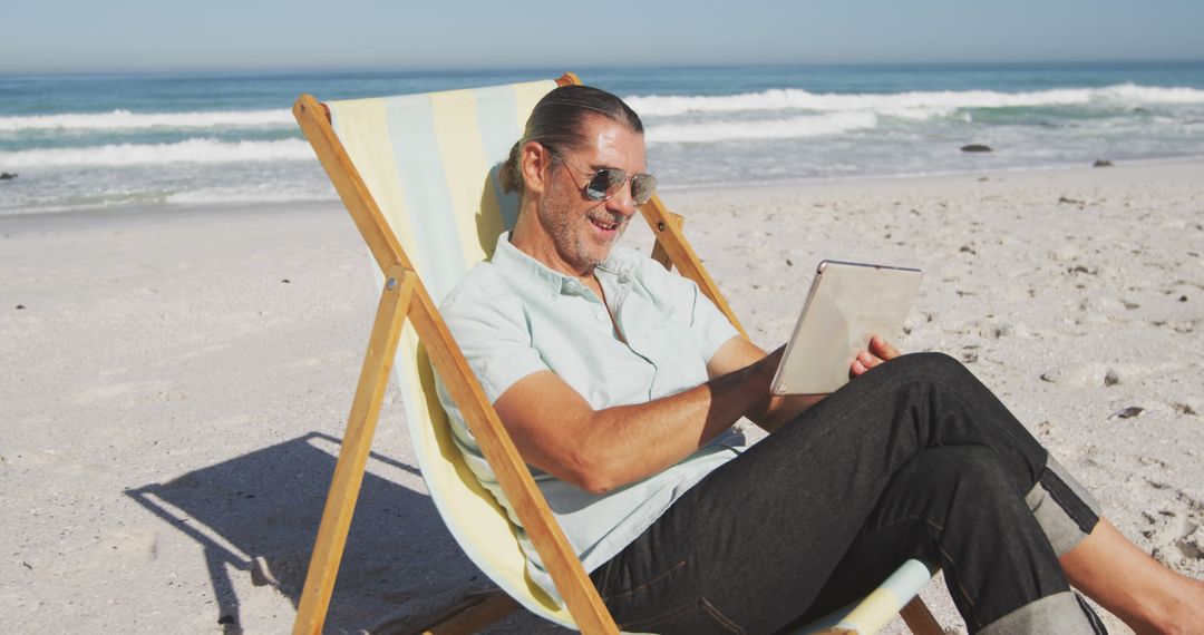 Man Relaxing on Beach Reading Tablet on Sunny Day - Free Images, Stock Photos and Pictures on Pikwizard.com