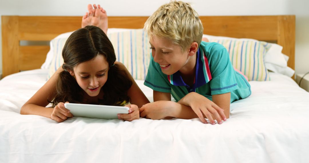 Children Using Tablet on Bed and Smiling Together - Free Images, Stock Photos and Pictures on Pikwizard.com