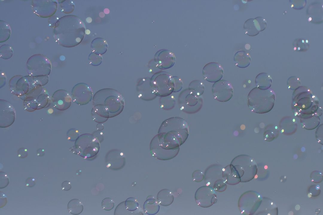 Floating Iridescent Bubbles Against Clear Blue Sky