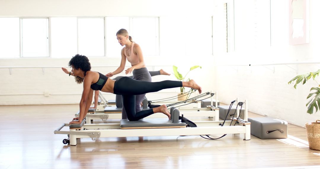 Women Practicing Pilates on Reformers in Bright Studio