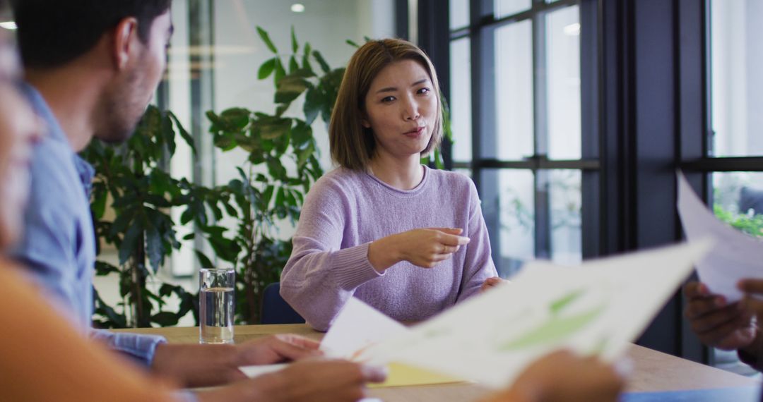 Diverse Team Collaborating in Modern Office with Laptops and Paperwork
