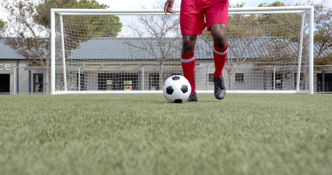 Low-Angle Soccer Player Controlling Ball at Goal on Artificial Turf Wearing Red Shorts