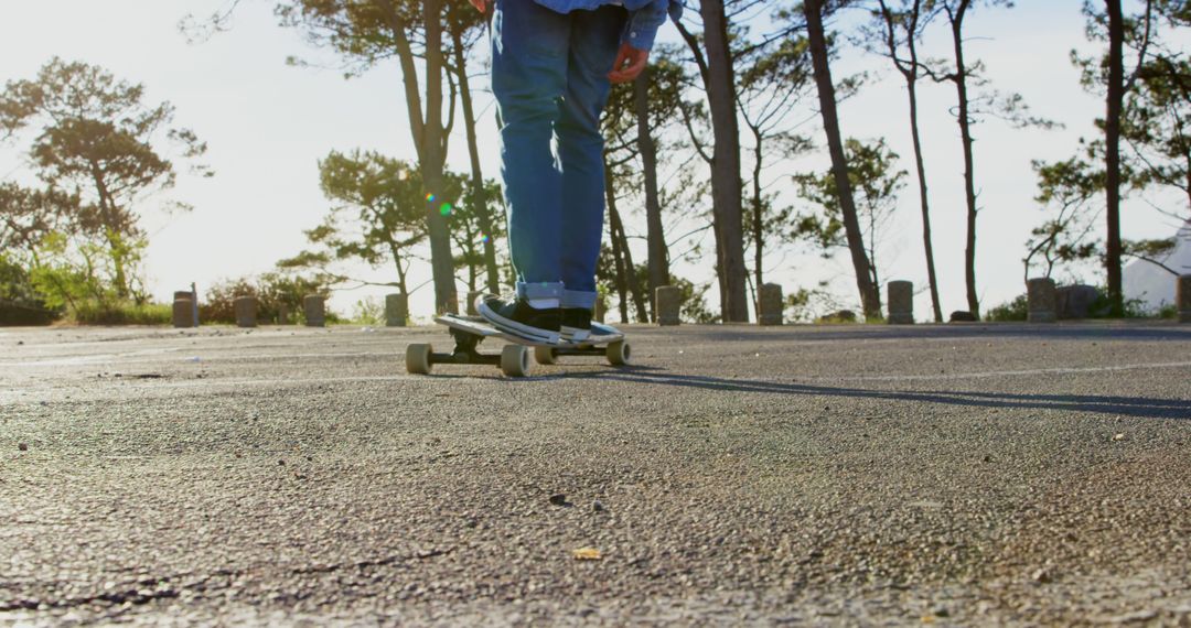 Person Skateboarding on Sunlit Asphalt Road in Nature - Free Images, Stock Photos and Pictures on Pikwizard.com