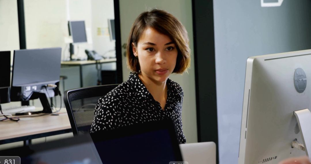 Focused Female Office Worker at Desk in Modern Workspace