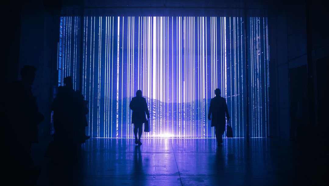Silhouetted commuters walking through neon LED portal with vertical blue light curtains
