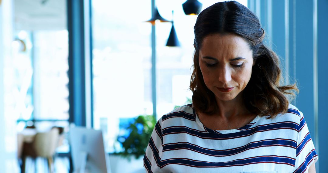 Pensive Woman with Striped Shirt in Modern Office - Free Images, Stock Photos and Pictures on Pikwizard.com