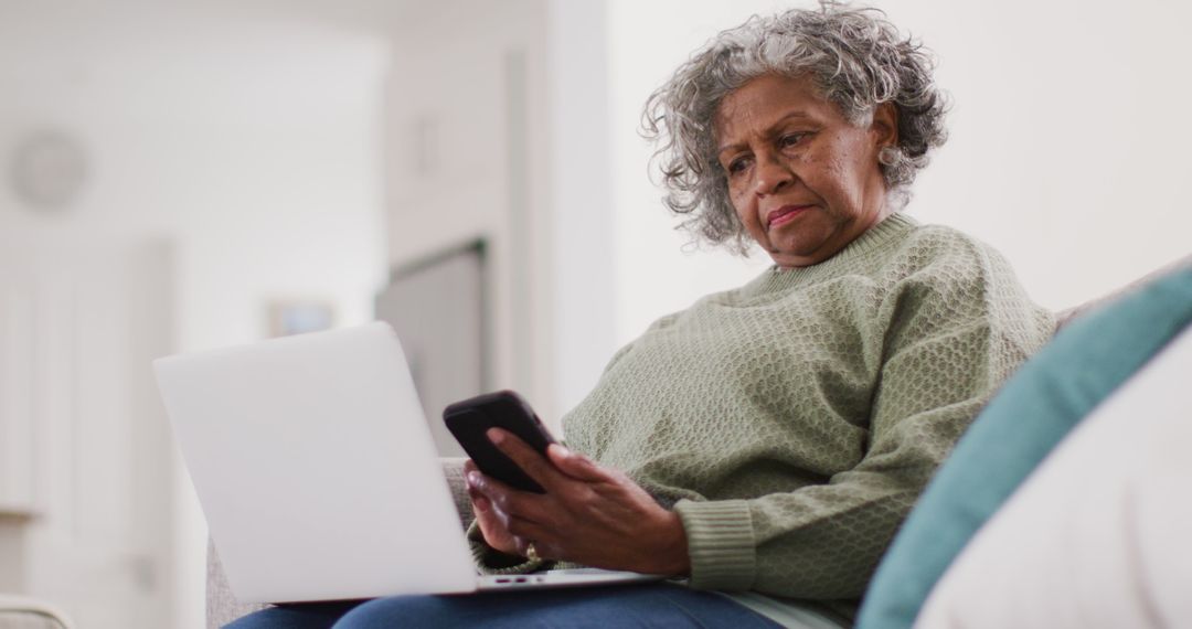 Senior Woman Using Smartphone and Laptop in Living Room - Free Images, Stock Photos and Pictures on Pikwizard.com