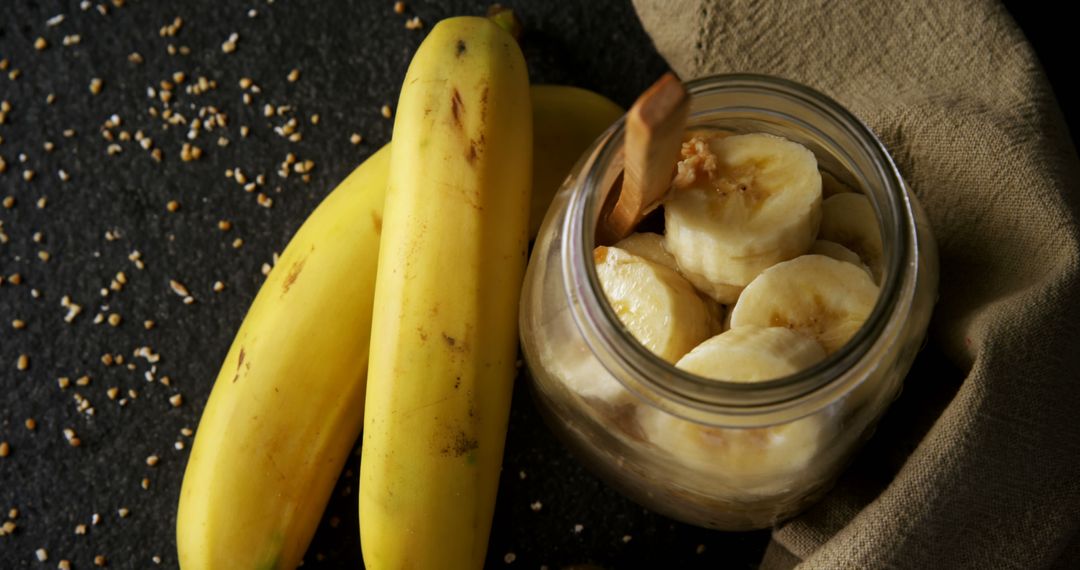 Fresh Sliced Bananas in Jar with Whole Bananas on Dark Surface - Free Images, Stock Photos and Pictures on Pikwizard.com