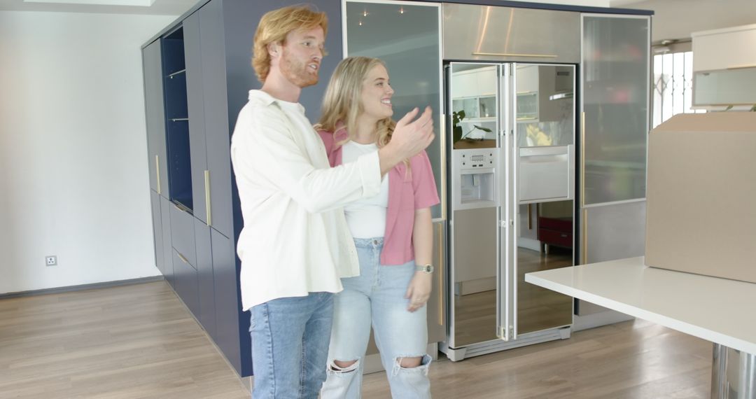 Happy Couple Unpacking in New Kitchen with Cardboard Box