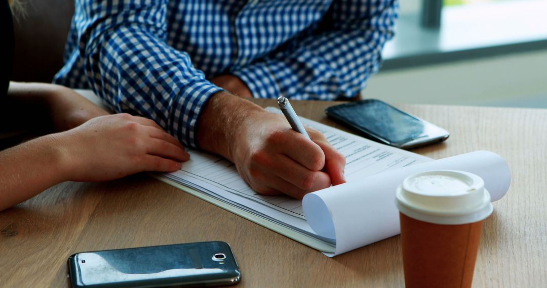 Close-Up of People Working on Document with Coffee and Smartphones - Free Images, Stock Photos and Pictures on Pikwizard.com