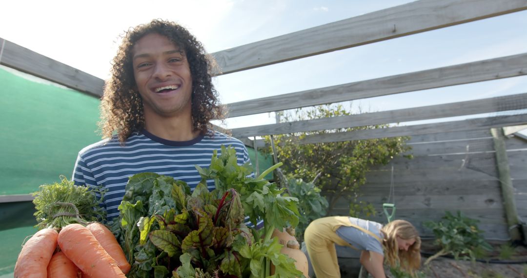 Young Man Holding Fresh Vegetables in Urban Garden - Free Images, Stock Photos and Pictures on Pikwizard.com