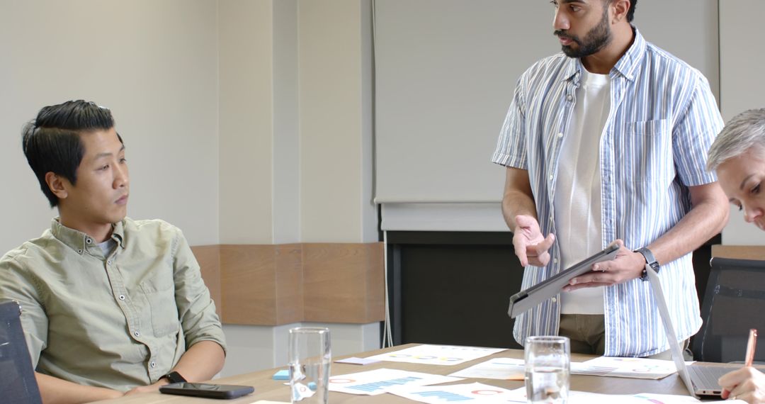 Diverse Team Discussing Insights with Tablet in Meeting Room