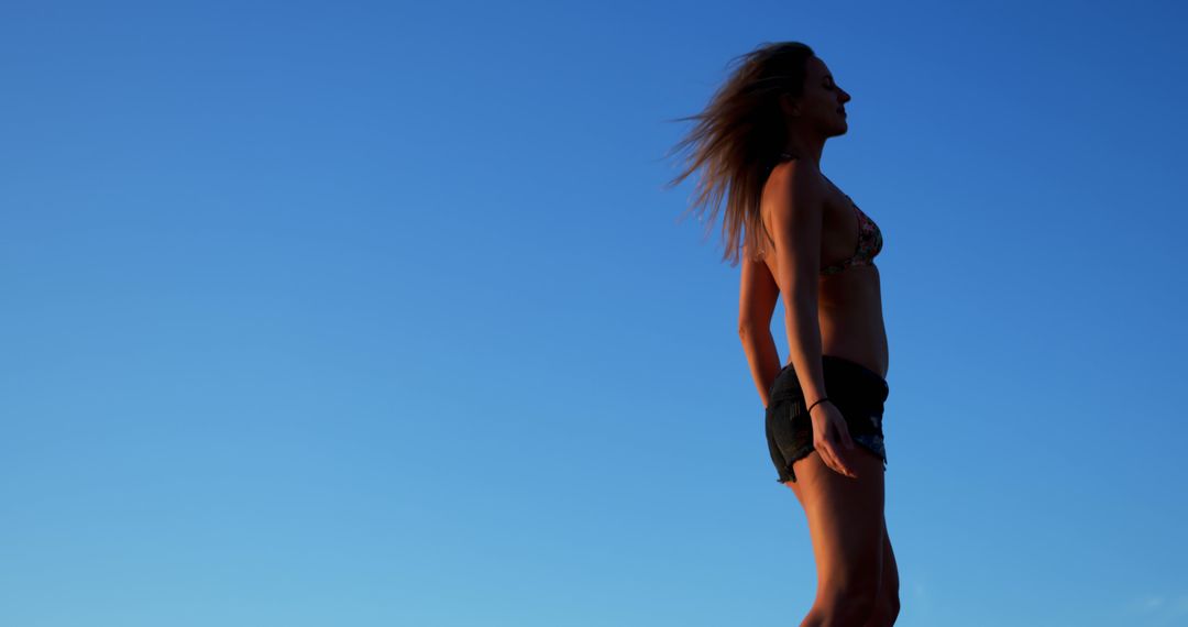 Woman Enjoying Warm Sunset Against Clear Blue Sky - Free Images, Stock Photos and Pictures on Pikwizard.com