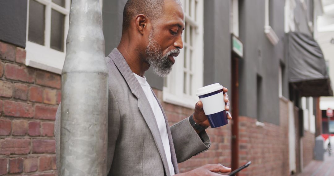 Businessman Enjoying Coffee While Checking Smartphone on City Street - Free Images, Stock Photos and Pictures on Pikwizard.com