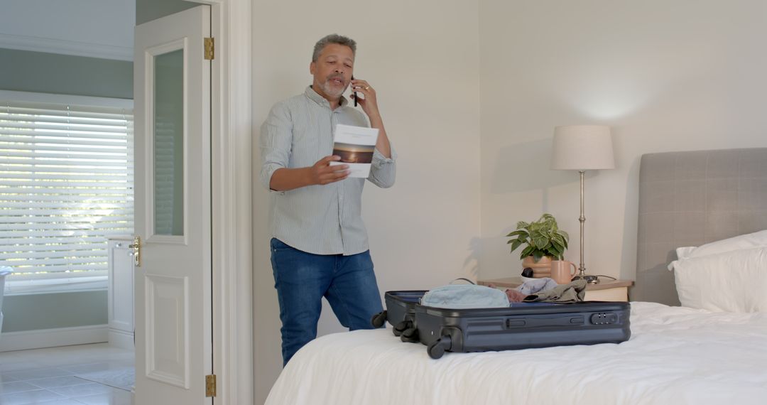 Man Packing Suitcase and Talking on Phone in Bedroom Before Travel