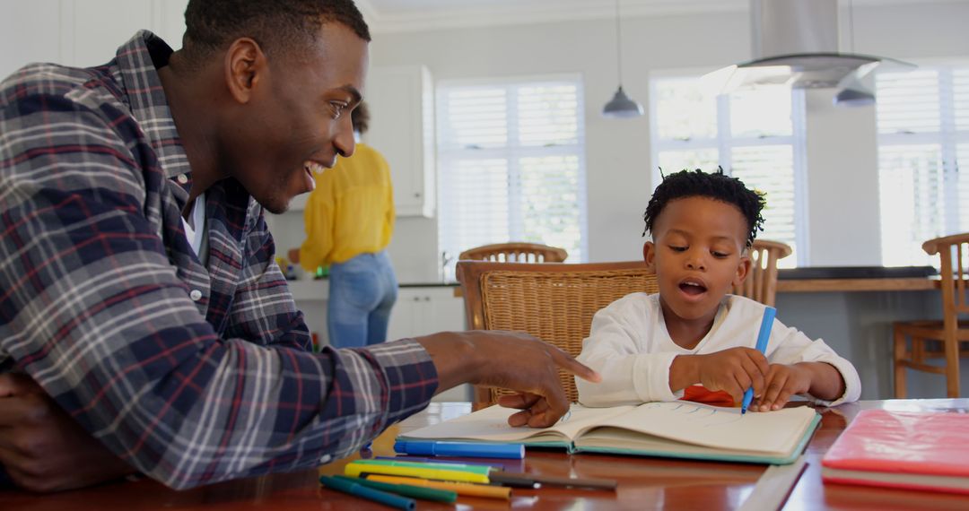 African American father helping young son with homework at kitchen table - Free Images, Stock Photos and Pictures on Pikwizard.com